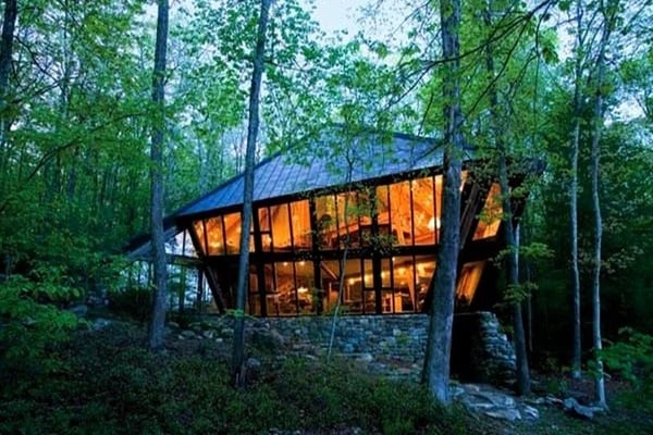 Modern glass house surrounded by forest